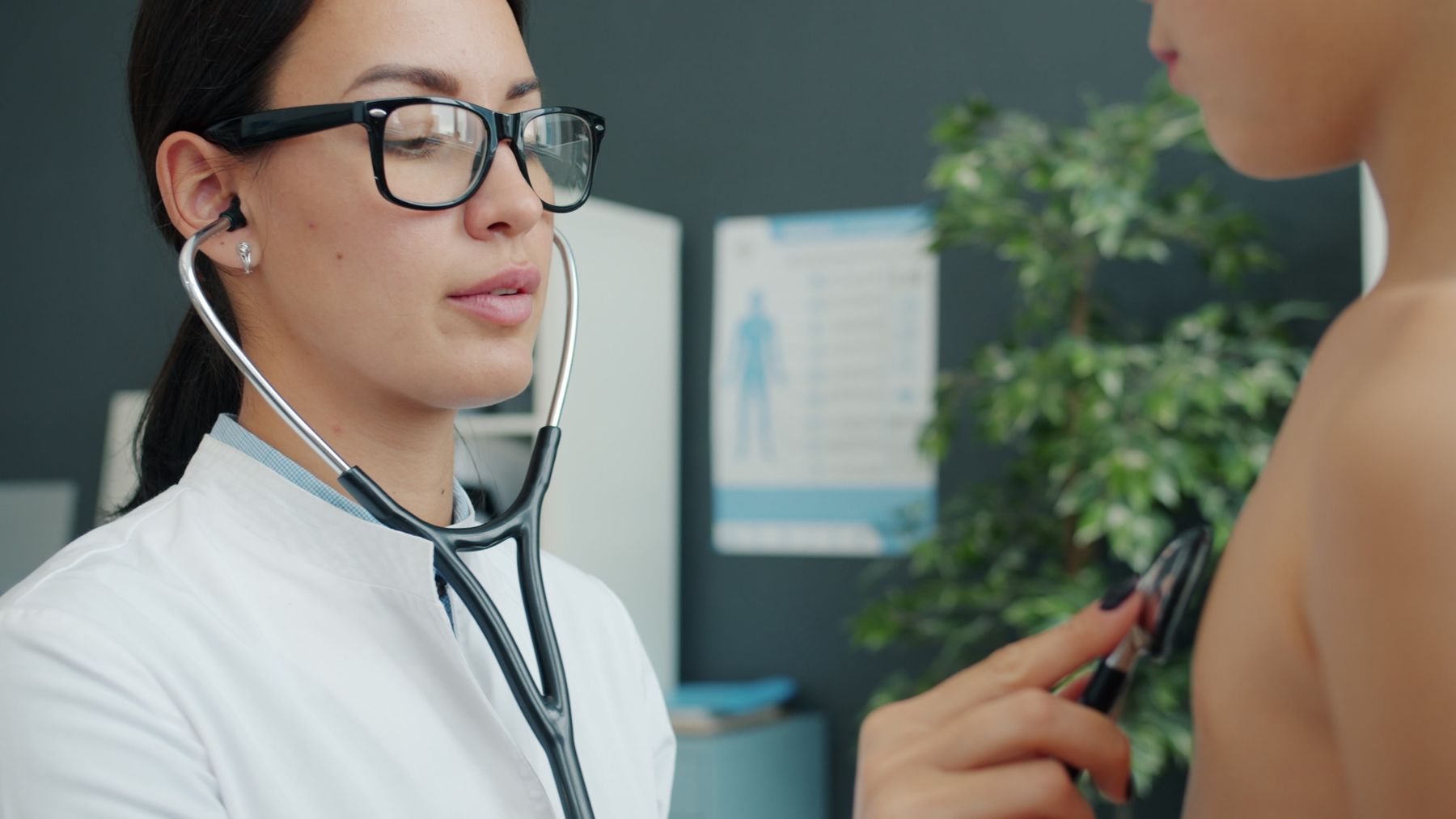 Doctor performing a health checkup on a child with a stethoscope, representing a sports physical exam