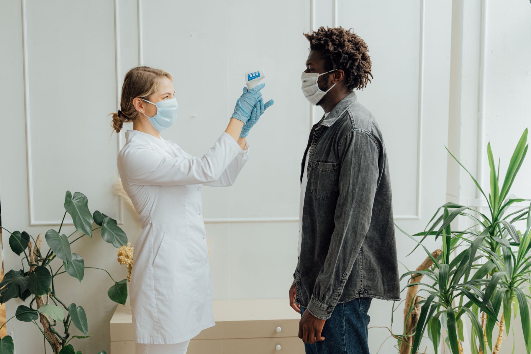 A healthcare provider checking a patient's temperature during a clinic visit