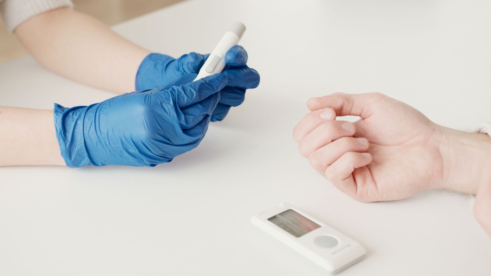 A healthcare worker checks a patient blood sugar level with a glucometer