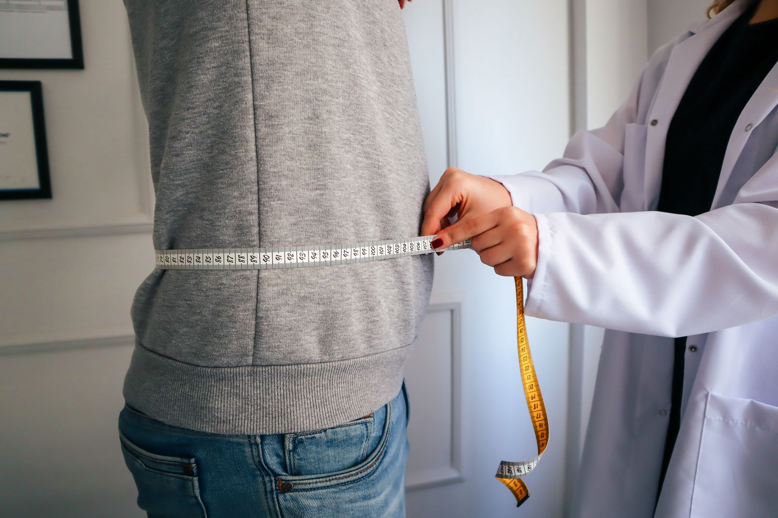 Dietitian measuring a patient waist during a weight management consultation